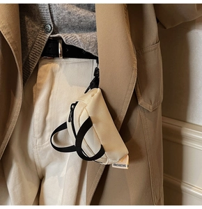 Close-up of beige canvas mini pouch with black strap hanging on a person belt
