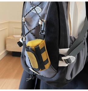 Detail einer gelben taktischen Mini-Tasche mit Schnellverschluss an einem grauen Rucksack
