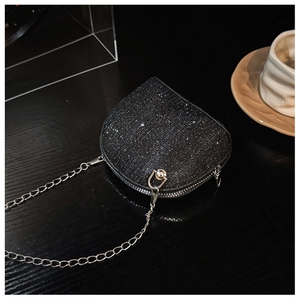 Macro detail of heart-shaped mini bag featuring black sequins and silver chain strap