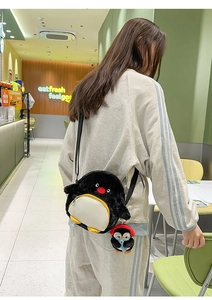 Schwarze Plüsch-Pinguin Umhängetasche mit Mini-Anhänger, getragen von einem Model
