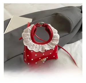 Detail of red polka dot mini bag with white lace collar and round metal handle