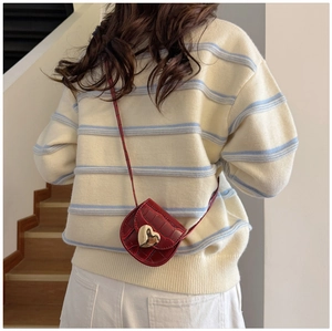 Sac bandoulière enfant rouge à motif pierre avec boucle cœur dorée en scène lifestyle