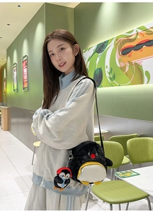 Detail einer süßen Pinguin Plüschtasche getragen von einem Model in einem grünen Café