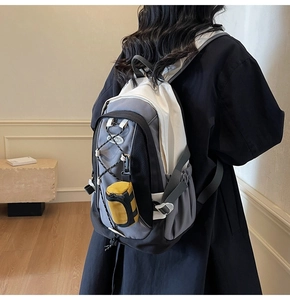 Detail eines grauen Wanderrucksacks mit Bungee-System und gelber Zylinder-Tasche