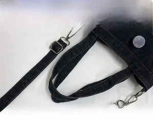 Detail view of denim bucket bag with adjustable strap and decorative grey fur ball