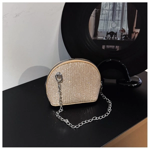 Close-up of golden rhinestone shell bag with metallic chain and zipper detail