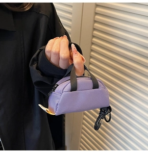 Handheld view of a mini purple nylon coin pouch showing its compact size and hook