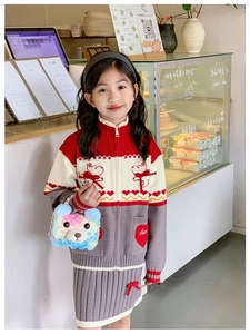 Detail of colorful plush bear bag and knitted girls' outfit with heart patterns