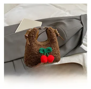 Close-up of brown faux fur mini bag featuring hand-knitted cherry decor and leather strap