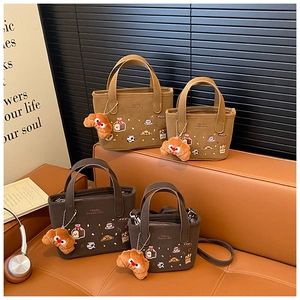 Detalle de mini bolsos tote bordados con colgantes de croissant de peluche en sofá