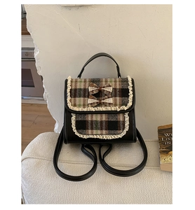 Detail of plaid student backpack with vintage lace trim and bow accents on soft surface