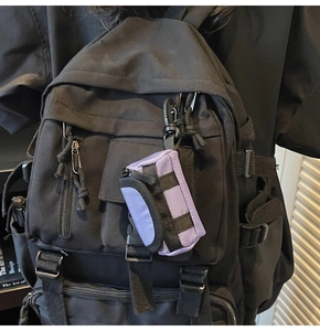 Lila Mini-Zubehörtasche aus Nylon mit Karabiner an einem schwarzen Rucksack