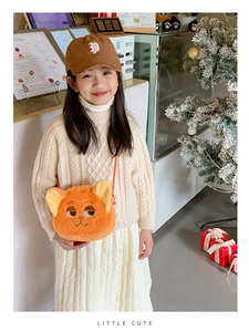 Close-up of orange plush fox bag with embroidery on a child model in a warm cafe