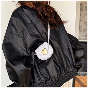 Détail d'un mini sac bandoulière blanc à texture crocodile avec un fermoir cœur doré