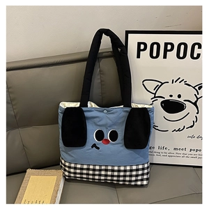 Close-up of cute cartoon dog tote bag with blue fabric and checkered bottom on a sofa