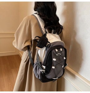 Detail of trendy utility mini pouch accessory hanging on a tricolor nylon backpack