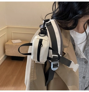 Close-up of white mini canvas pouch hanging on a backpack strap for small items