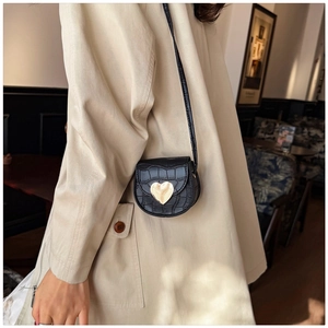 Détail d'un mini sac bandoulière texture croco avec grande boucle cœur dorée