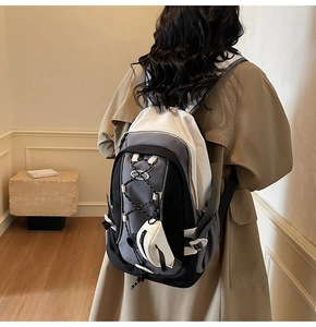 Detail of a techwear backpack featuring grey splicing and a mini white coin pouch attachment