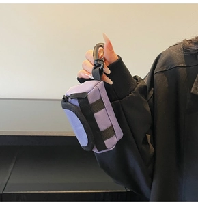 Detail der lila Mini-Tasche aus Nylon mit schwarzem Gurt und Haken zeigt die kompakte Größe