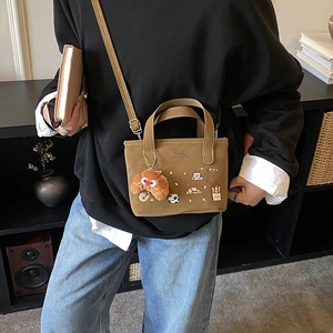 Bolso bandolera infantil de lona marrón con bordado y colgante de croissant de peluche