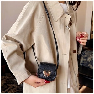 Détail du mini sac bandoulière noir motif pierre avec une boucle cœur dorée