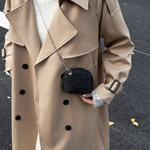 Kids black sequin shell bag with silver chain strap shown on a khaki coat model