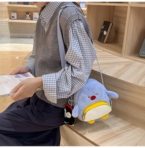 Detail der blauen Plüsch-Pinguin-Tasche mit gelber Reißverschlusstasche und Anhänger