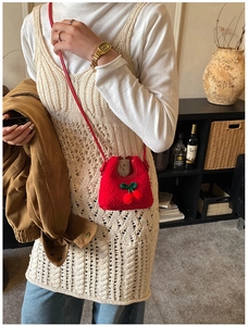 Detailed view of kids' red cherry plush crossbody bag worn with cozy autumn knitwear
