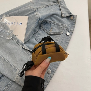 Detail of yellow nylon mini coin purse with black carabiner clip on denim background