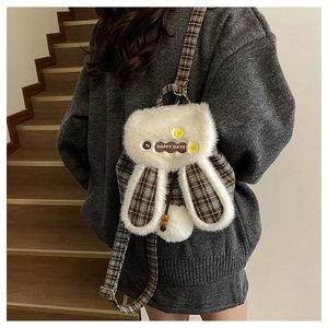 Detail of cute fluffy rabbit backpack with long ears and plaid fabric on wooden stairs
