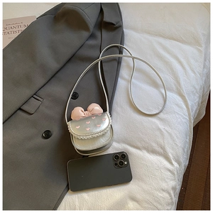 Comparaison de taille du mini sac argenté avec nœud rose sur veste grise