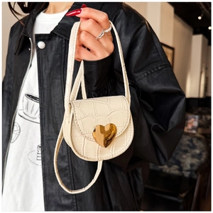 Détail du mini sac crème avec texture crocodile et fermoir rotatif en forme de cœur