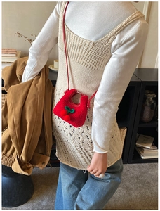 Close-up of fluffy red cherry crossbody bag showing plush texture and woven leaf detail