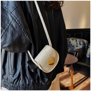 Détail du mini sac crème à motif croco avec fermoir en métal doré en forme de coeur