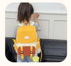 Détail d'un sac à dos enfant multicolore avec bretelles jaunes et patch logo