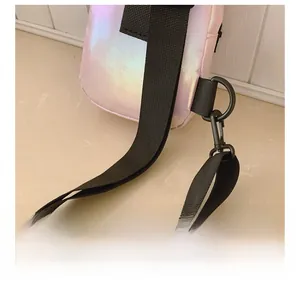 Dettaglio della tracolla regolabile in nylon nero sulla borsa rosa iridescente