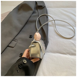 Détail d'un mini sac argenté avec cœur rose et bordure en dentelle blanche délicate