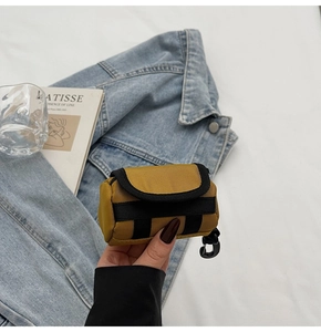 Nahaufnahme der gelben Mini-Kopfhörertasche mit Haken vor einer Denim-Jacke