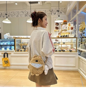 Detail of fluffy brown puppy crossbody bag with blue bib and embroidered cute lettering