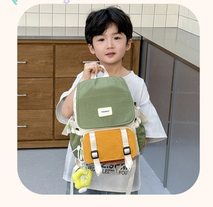 Détail du sac à dos enfant bicolore vert et jaune avec pendentif fleur en peluche