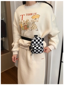 Dettaglio del borsello a scacchi per bambini indossato sopra una felpa beige moda