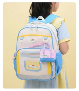 Détail d'un sac à dos enfant tricolore avec bretelles larges et mini pendentif décor