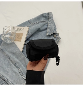 Nahaufnahme der schwarzen Mini-Nylontasche mit Clip an Jeansjacke für Kopfhörer