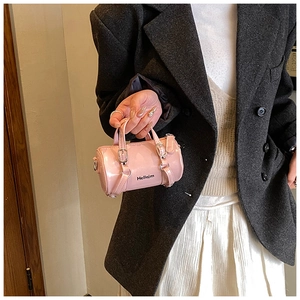 Gros plan du sac cylindrique rose en cuir verni avec inscription Hellojm chic