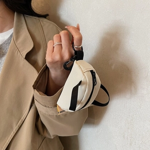 Mini off-white canvas backpack coin purse with metal carabiner held by a model