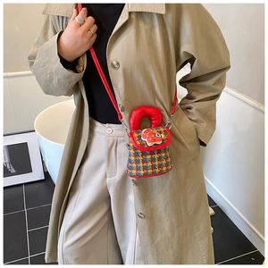 Détail d'un sac bandoulière enfant en tweed à carreaux avec breloque poupée rouge