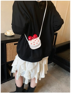 Détail du sac bandoulière blanc pour enfant avec nœud rouge et imprimés cœurs à dentelle