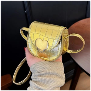 Détail de la boucle cœur dorée sur un mini sac besace avec texture de pierre