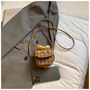 Close-up of mini plaid crossbody bag with knit flowers and bow on a grey blazer